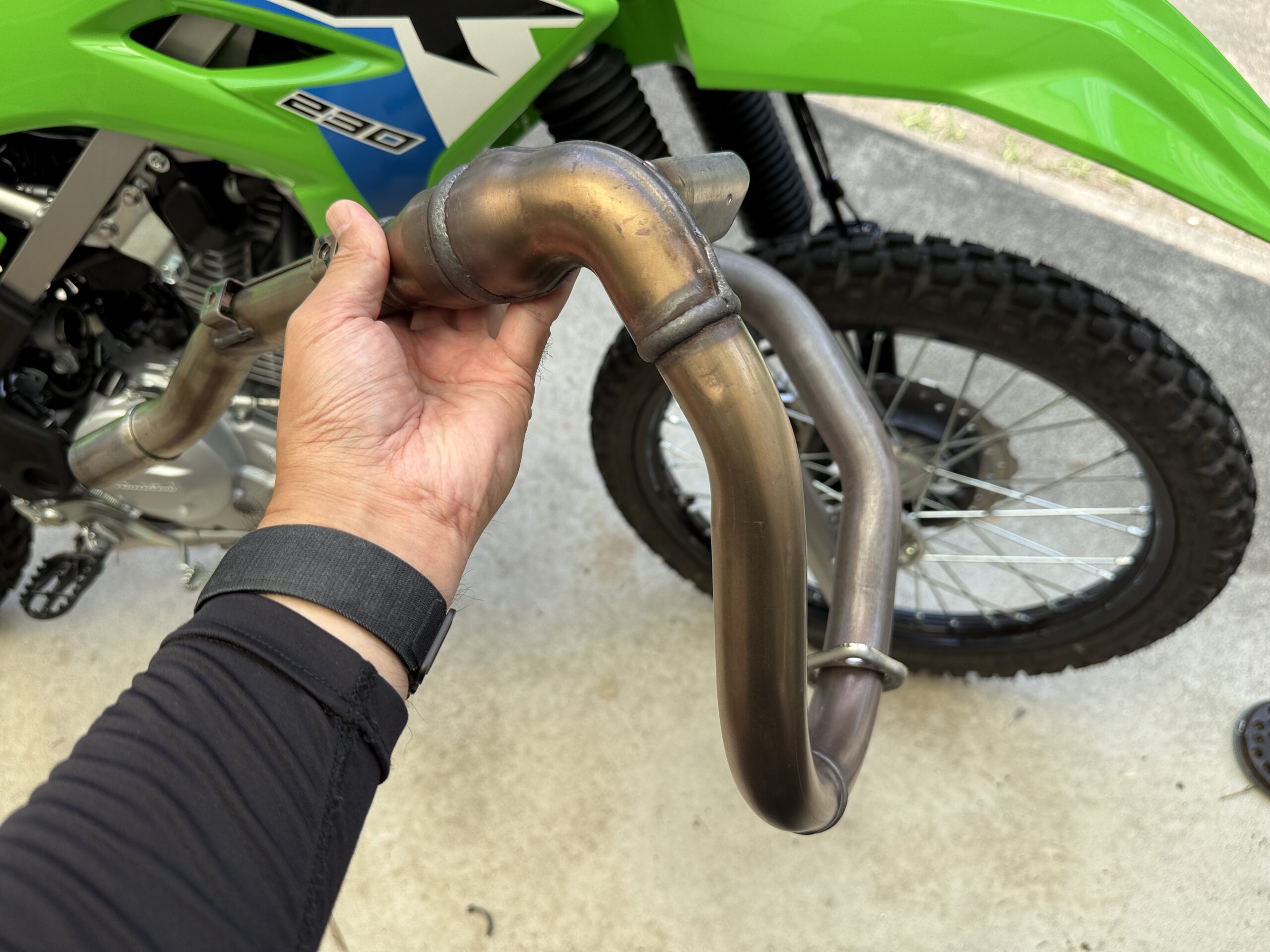 外れたKLX230のエキパイと左手