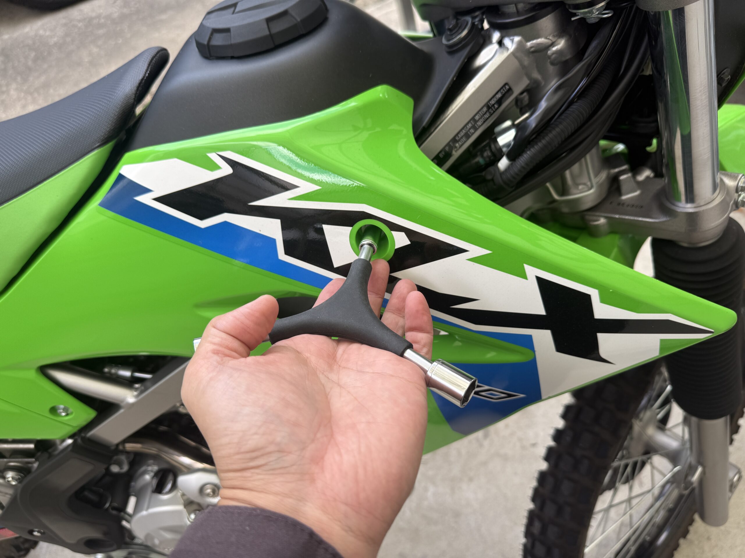 KLX230のサイドカウル固定ボルトに3WAYレンチを使用している様子